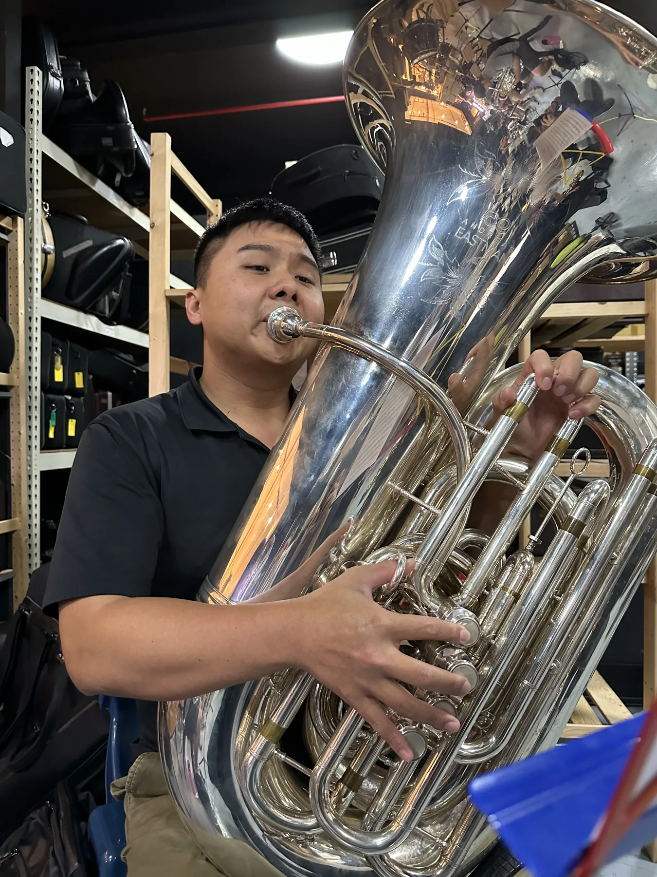 A TWA euphonium player smiling behind his instrument at rehearsal