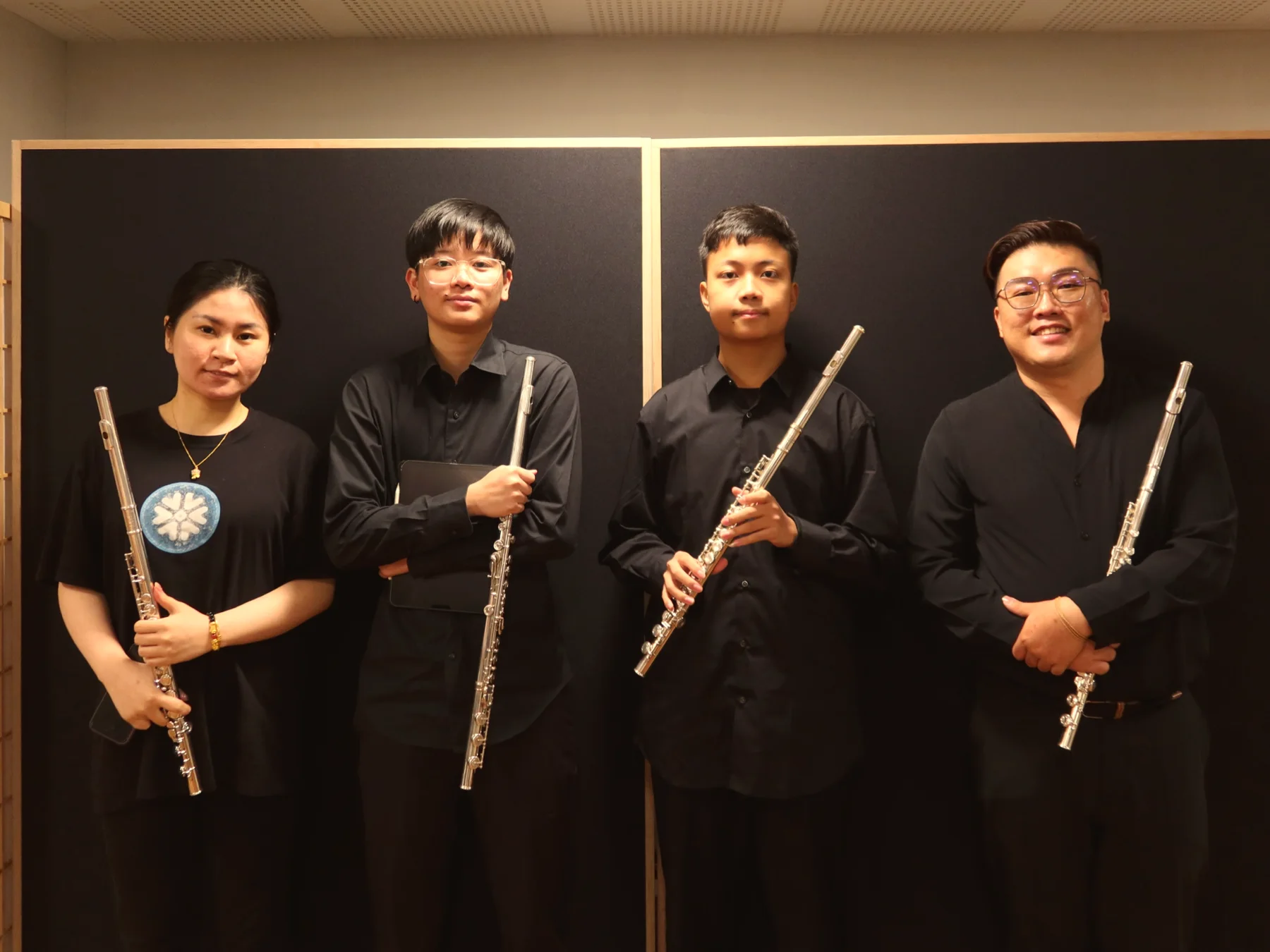 Four TWA flautists standing together with their flutes