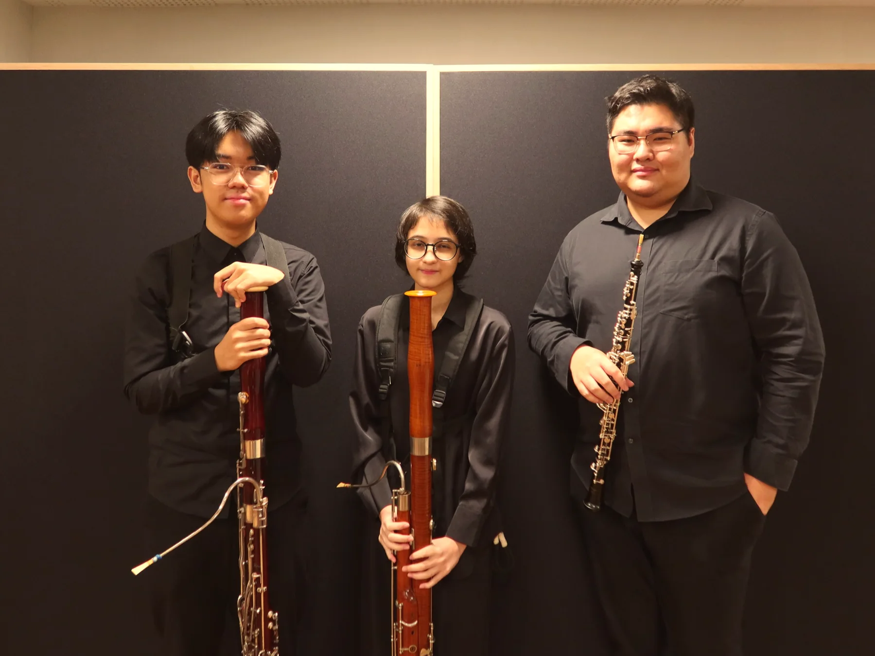 Three TWA woodwind players standing together with their bassoon and oboe