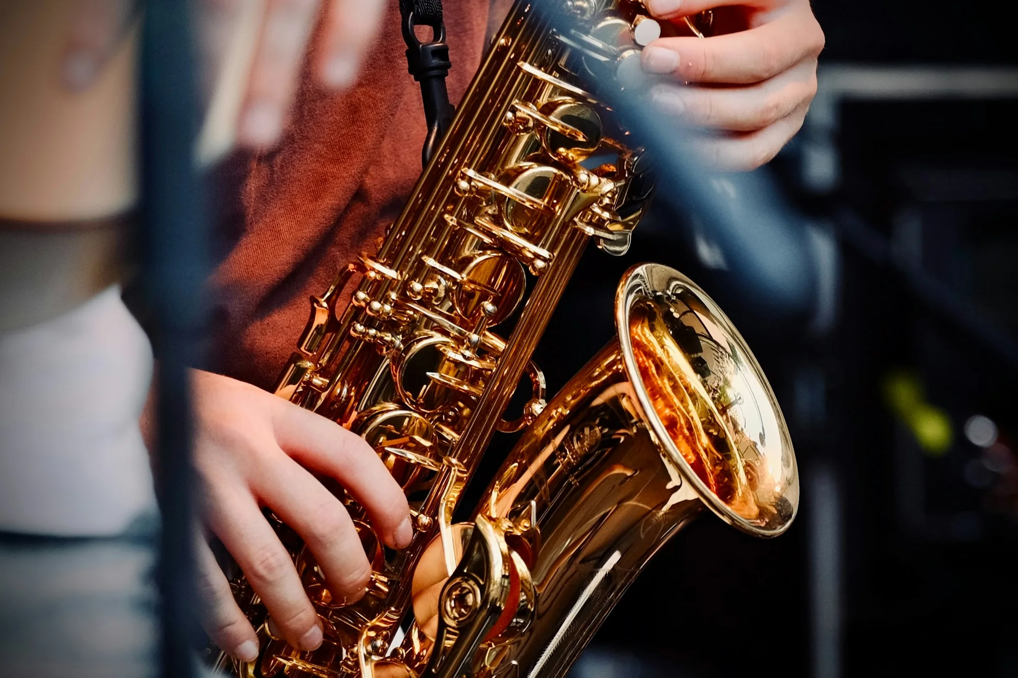 Close-up of a musician’s hands on the keys of a gold saxophone