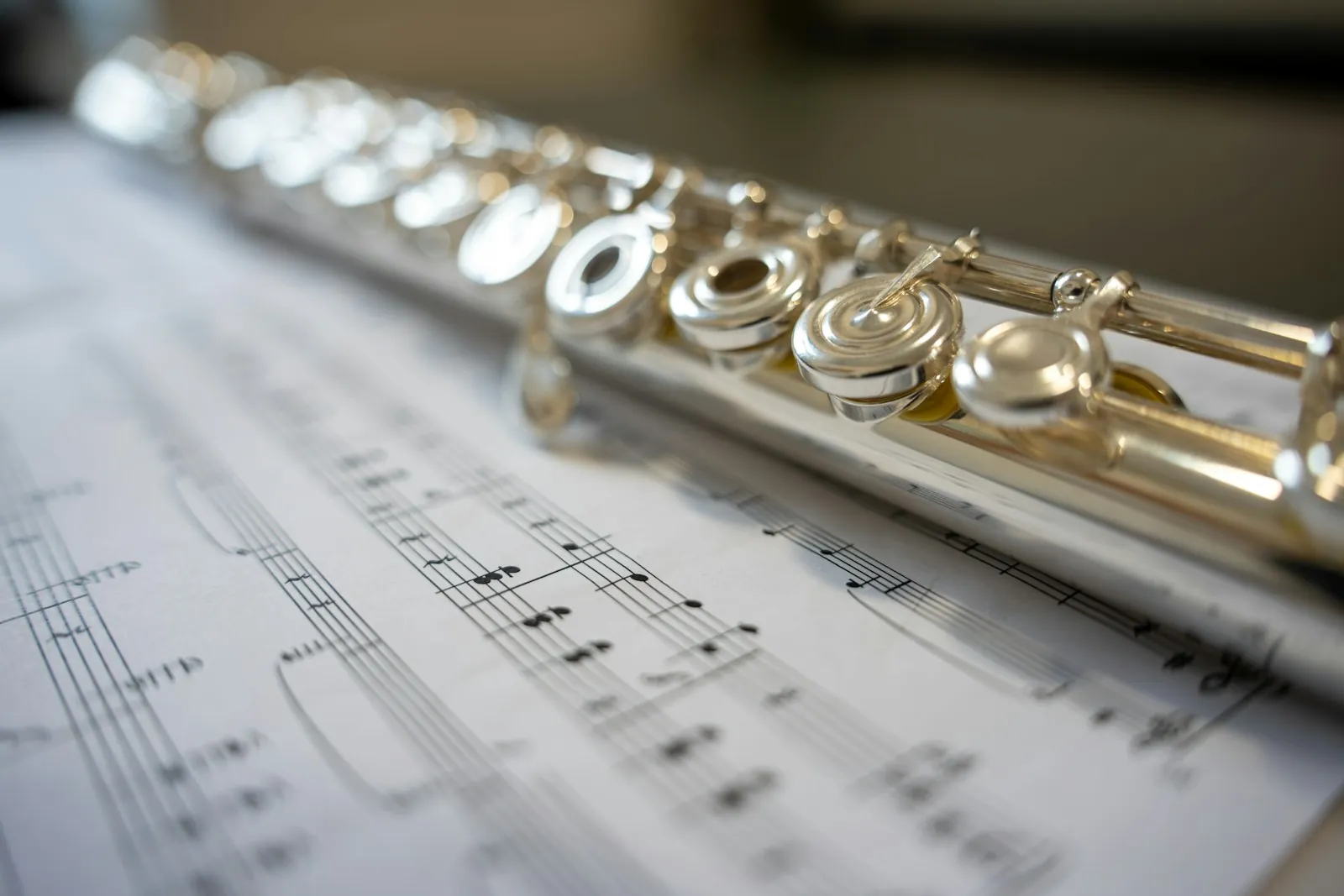 A silver flute resting on sheet music