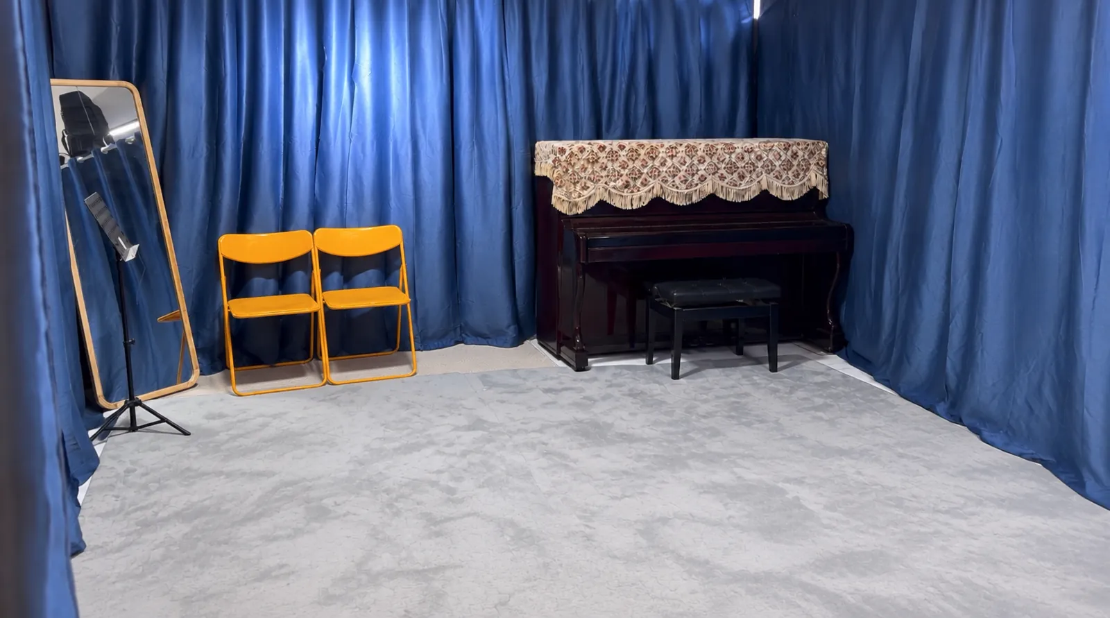The sound-treated TWA studio with blue acoustic curtains and an upright piano