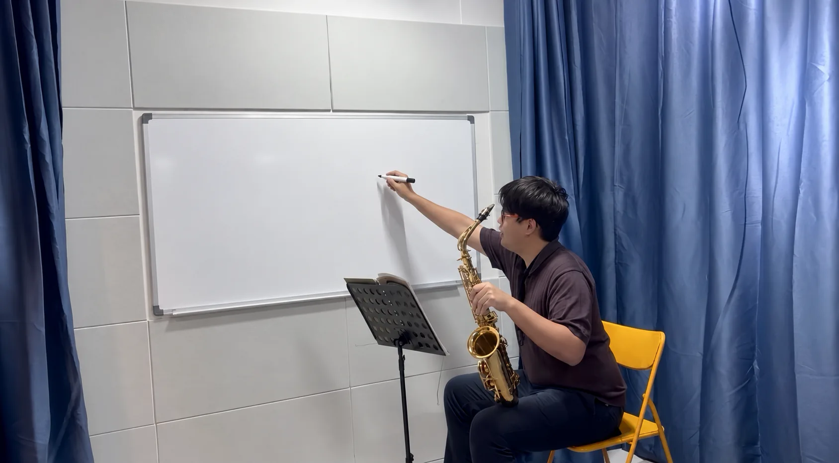 A TWA teacher at the whiteboard with a saxophone in the studio