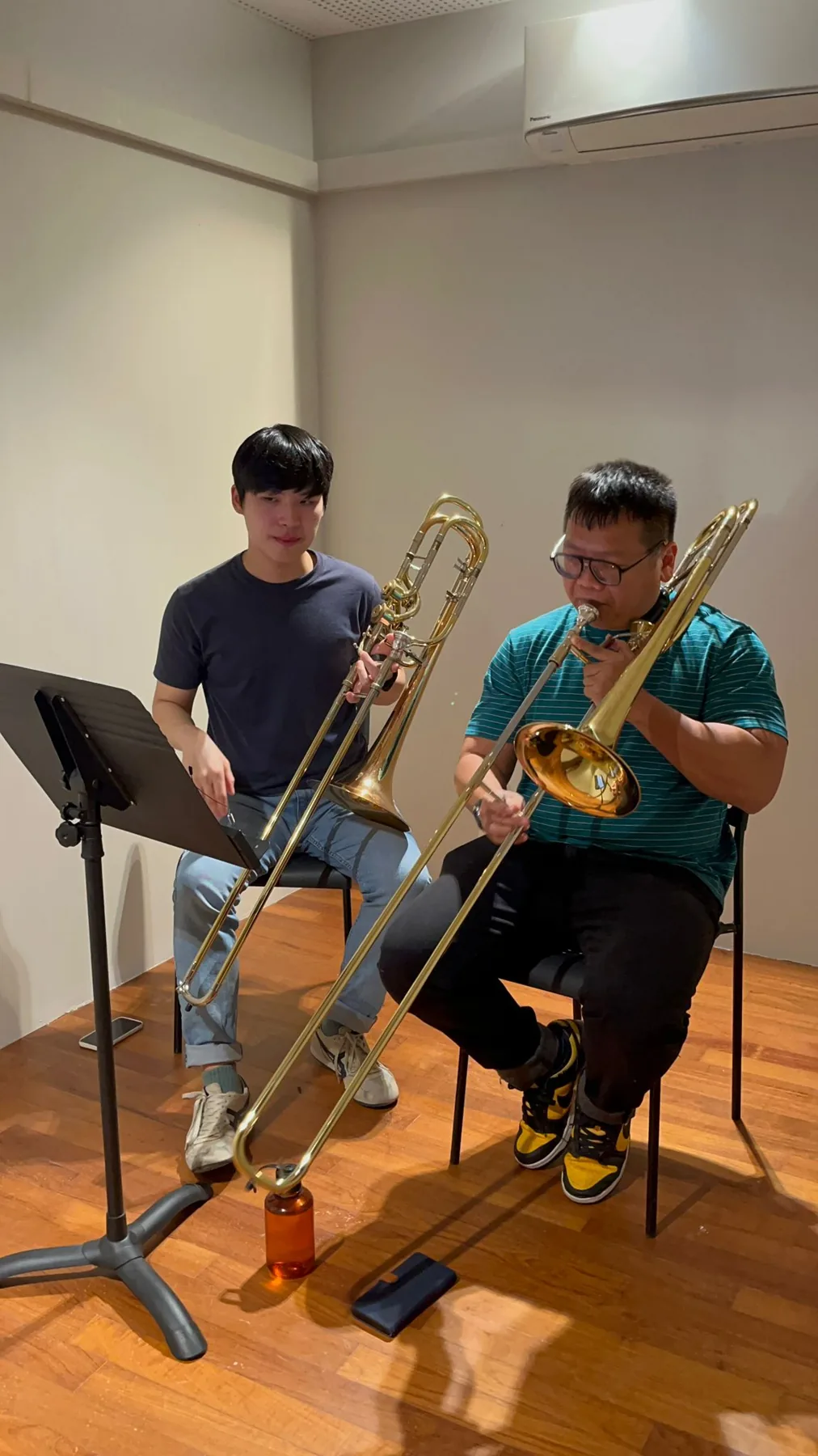 A TWA faculty member and a learner playing trombone side by side